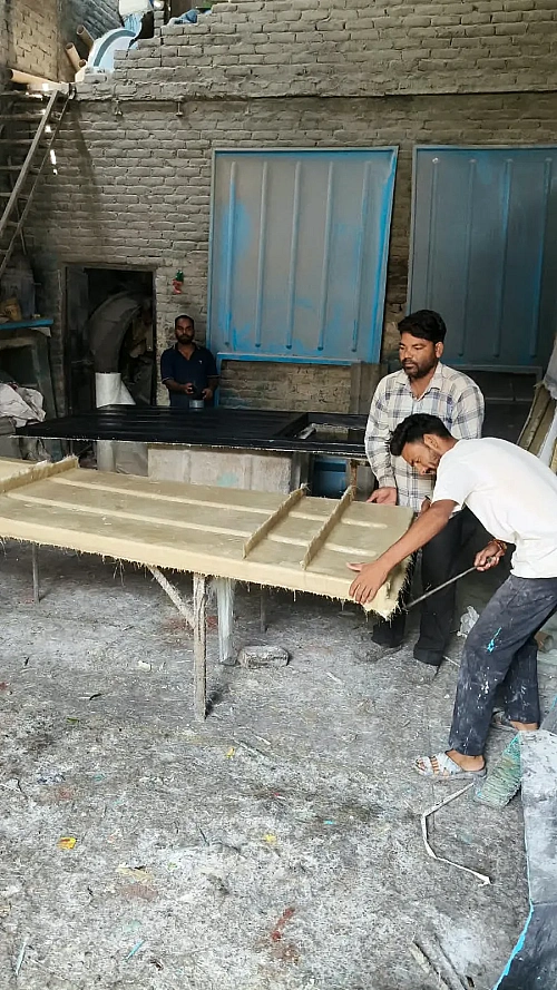 Workers fabricating an FRP panel on the moulding table